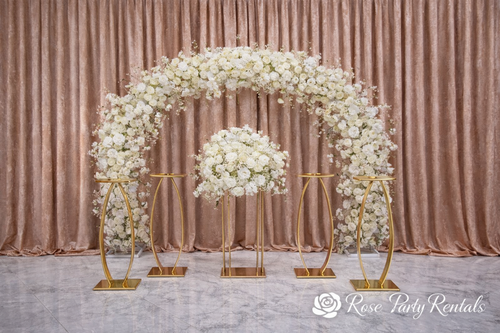 White floral arch with gold pedestals on blush drape