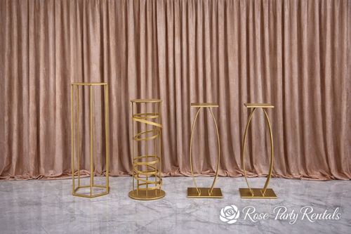 Assorted gold pedestal stands on blush drape
