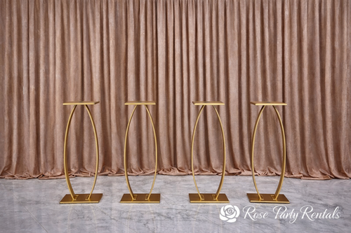 Gold oval pedestal stands on blush drape
