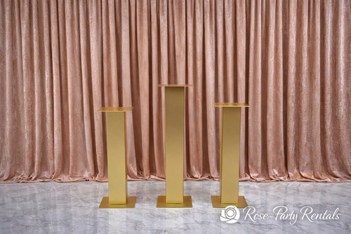 Gold square column pedestals on blush drape