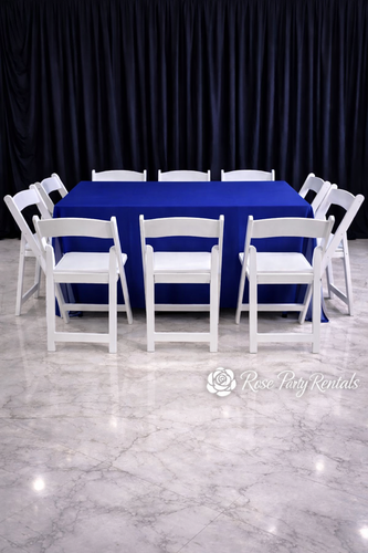 White folding chairs around rectangular table with royal blue linen